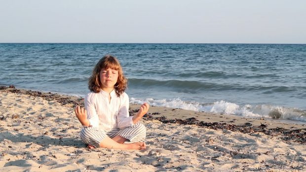 niña-meditando-playa-mar-sol