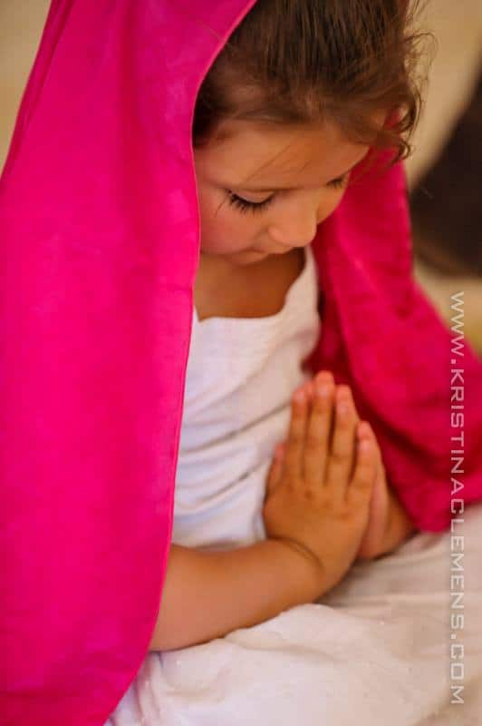 Niña rezando y una manta rosa